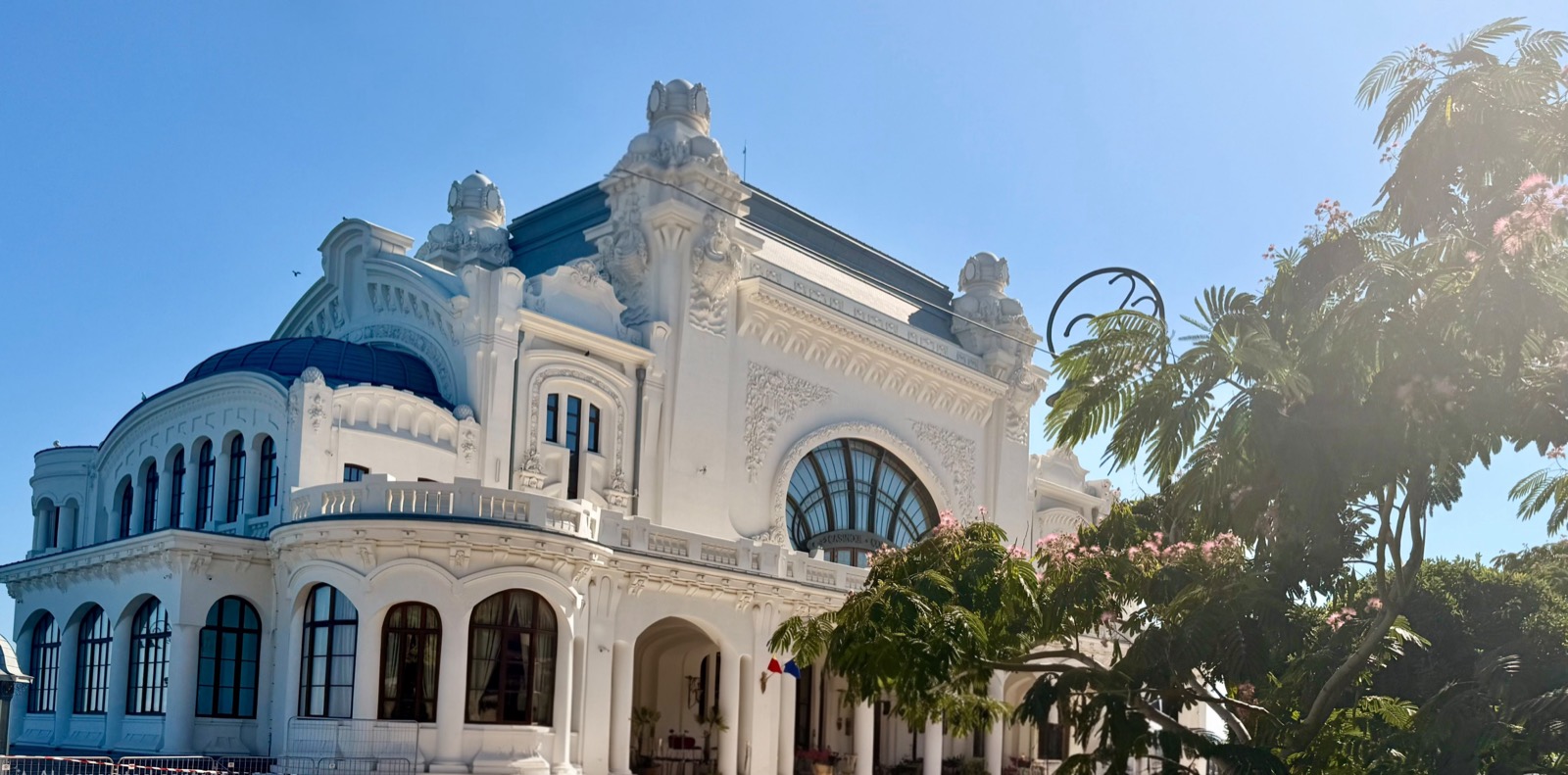 The Casino from the side, with its blue dome, Art Nouveau ornaments and a flowering silk tree on the right