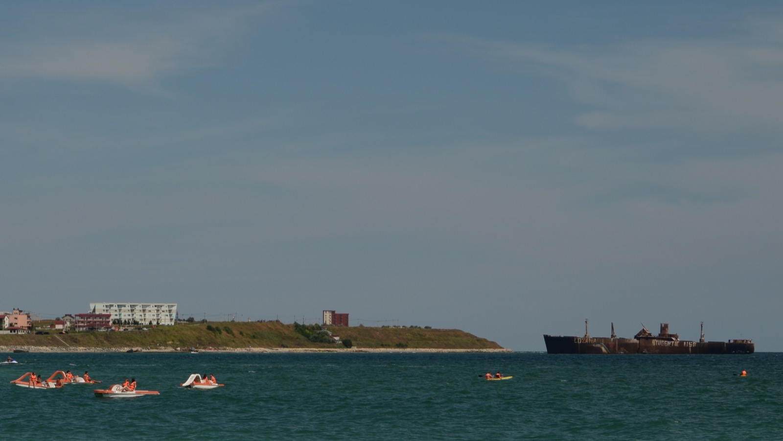 Tretboote auf dem Meer bei Costinești, dahinter die Landspitze nördlich des Badeorts und das Wrack der Evangelia