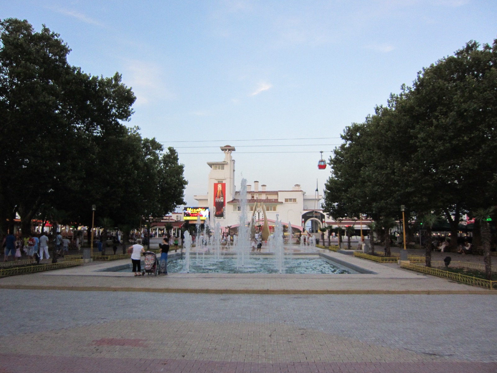 Fântâna arteziană de pe aleea care duce spre Cazino, cu turnul clădirii și o cabină a telegondolei în fundal