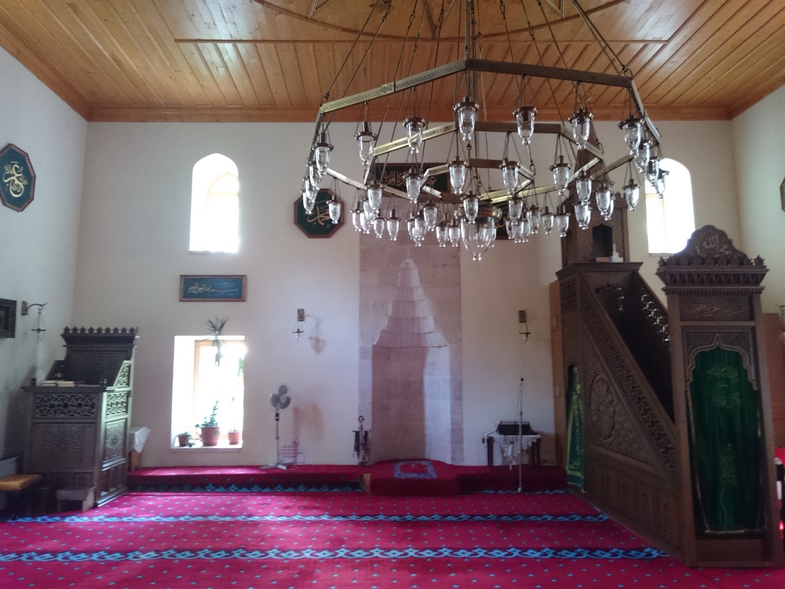 Interiorul moscheii, cu candelabrul mare, mihrabul, minbarul din lemn sculptat și covorul roșu