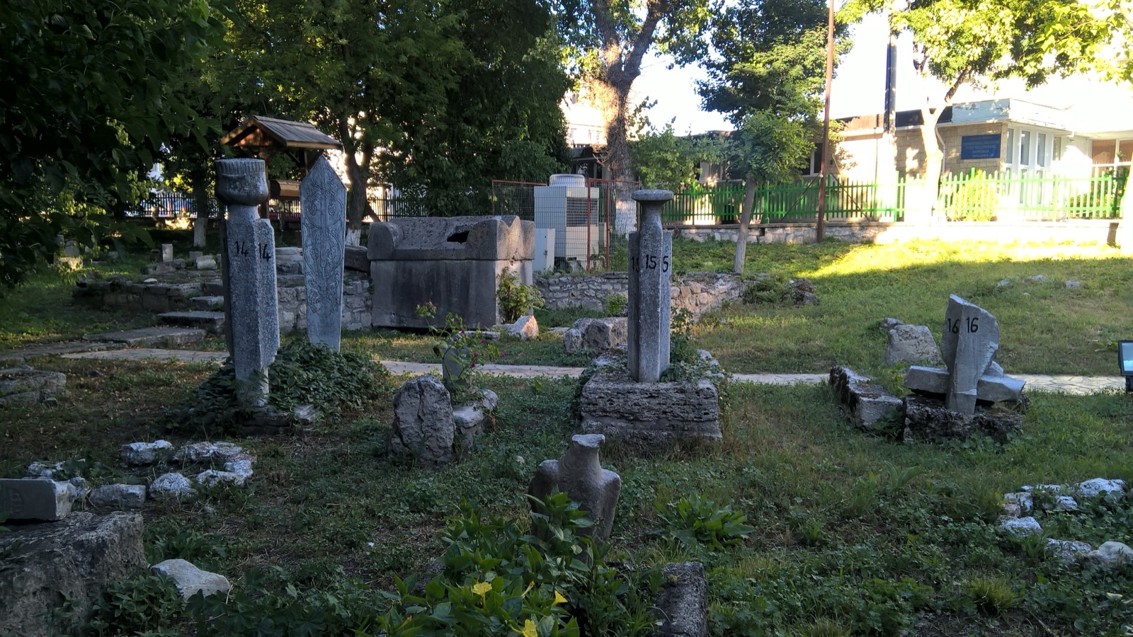 Pietre funerare vechi și un sarcofag de piatră în cimitirul musulman din curtea moscheii, printre copaci